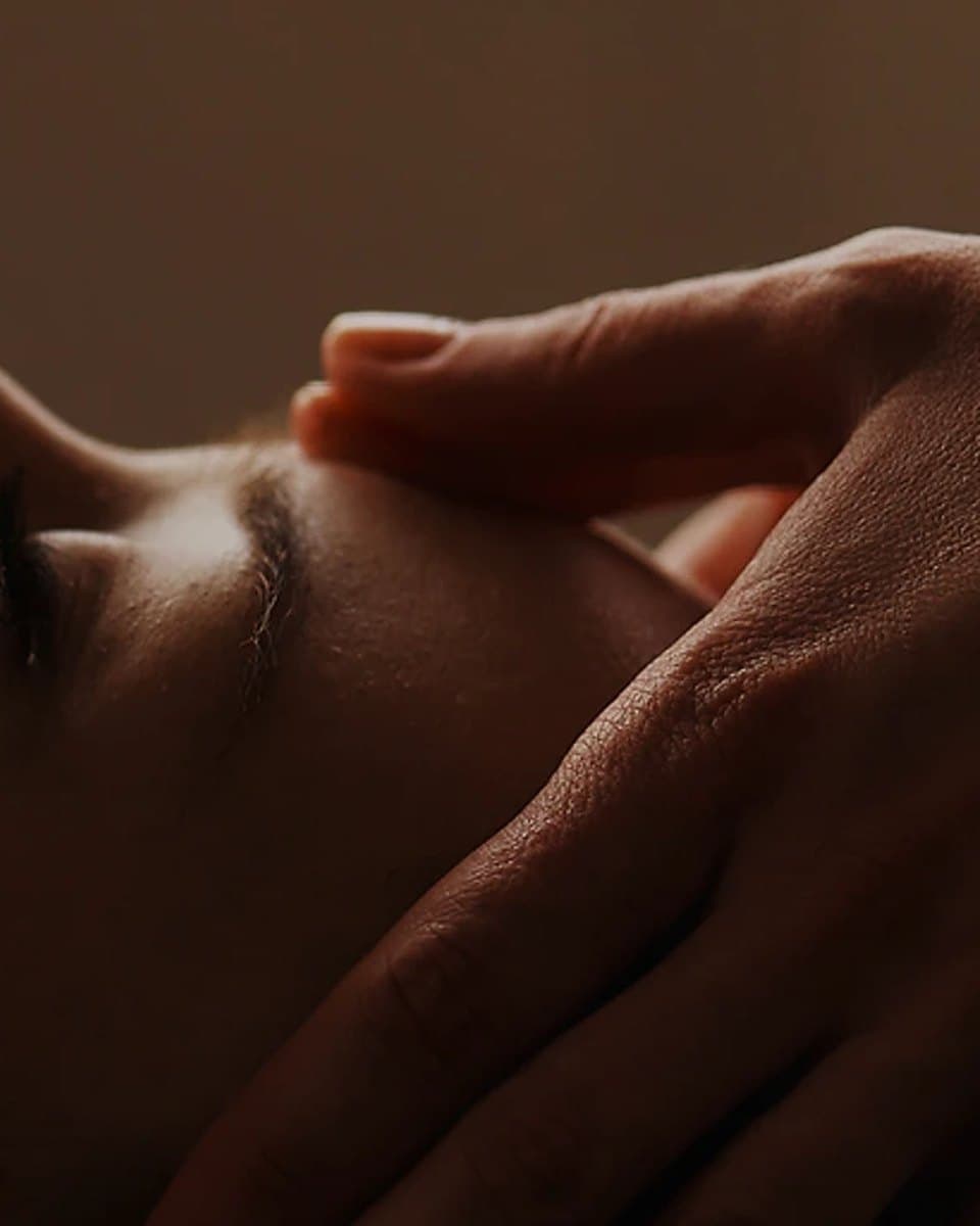 Mains posées sur la nuque et la mâchoire d'une personne allongée, en fin de séance