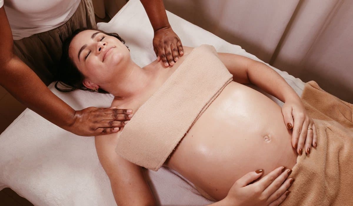 Mains d'un thérapeute posées sur le ventre d'une femme enceinte allongée