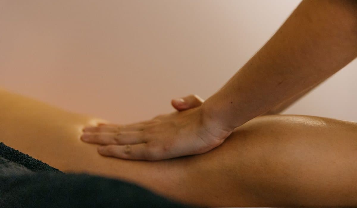 Avant-bras du thérapeute glissant le long de la cuisse d'une personne allongée